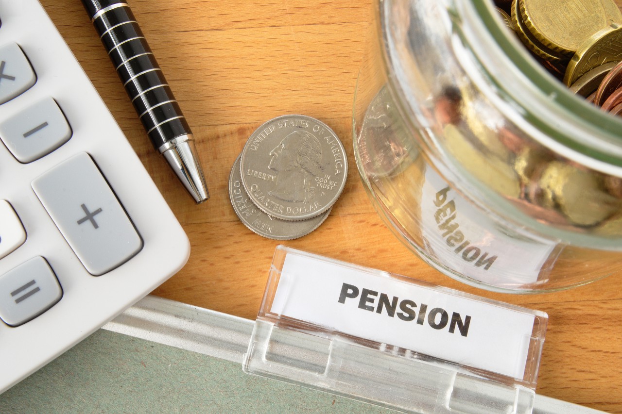 Pension file with calculator, pen, coins and glass jar