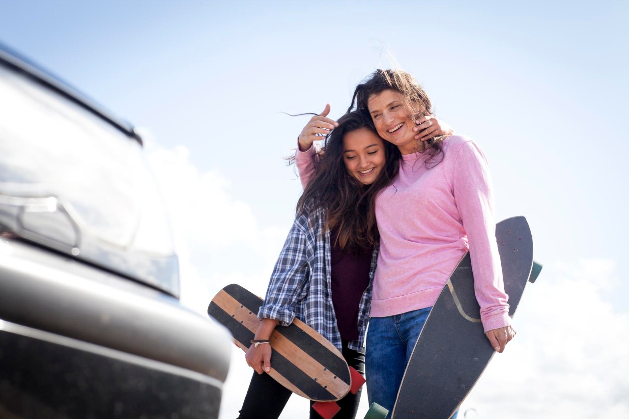 Middle age woman and her teenage daughter skateboard, next to the sea in bournemouth England in the summer